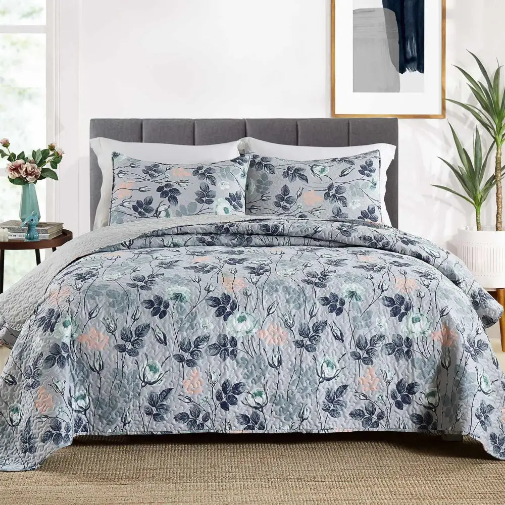 Gray quilted bedspread with navy pink and green floral pattern in patchwork rust and cream coverlet bedding set