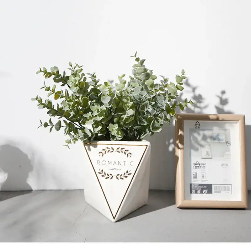 White triangular ceramic planter with gold trim and romantic text design featuring decorbites eucalyptus leaves artificial arrangement
