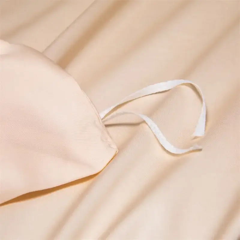Beige satin pillowcase with white drawstring in peach satin cooling cotton solid bedding set for bedroom use