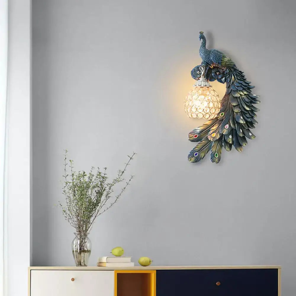 Peacock blue and gold wall sconce with iridescent feathers and clear crystal dome shade for bedroom lighting