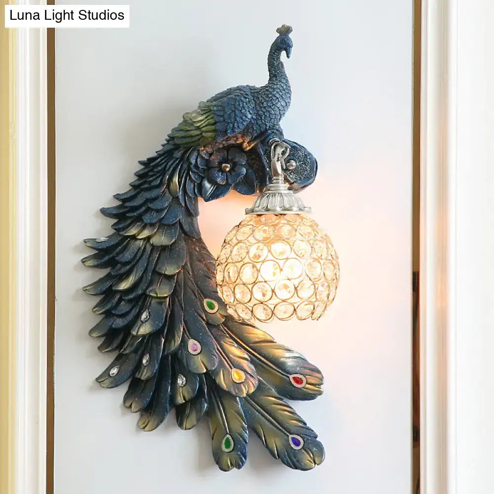 Peacock blue and gold wall sconce with dark feathered body and clear crystal dome shade for bedroom lighting