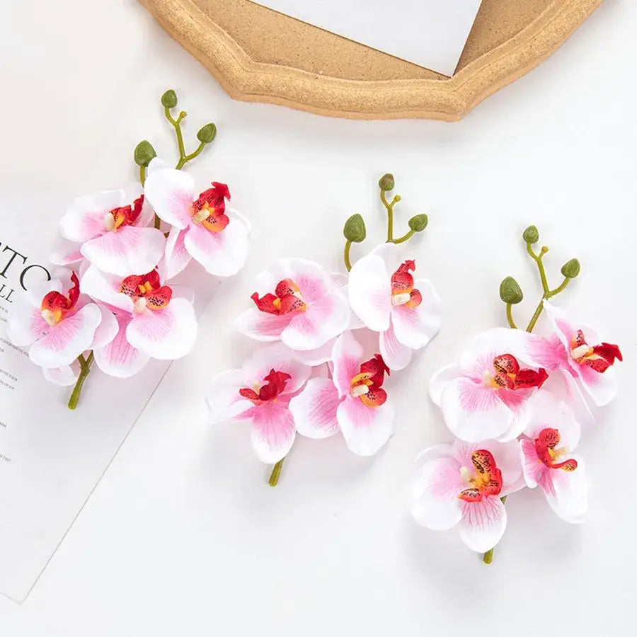 Pink and white artificial flower stems with red centers for wedding garden arch decor featuring orchid clusters