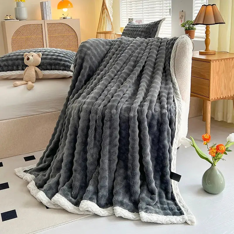 A plush gray throw blanket with a soft white fleece border and ribbed pattern from decorbites cozy faux rabbit fur collection