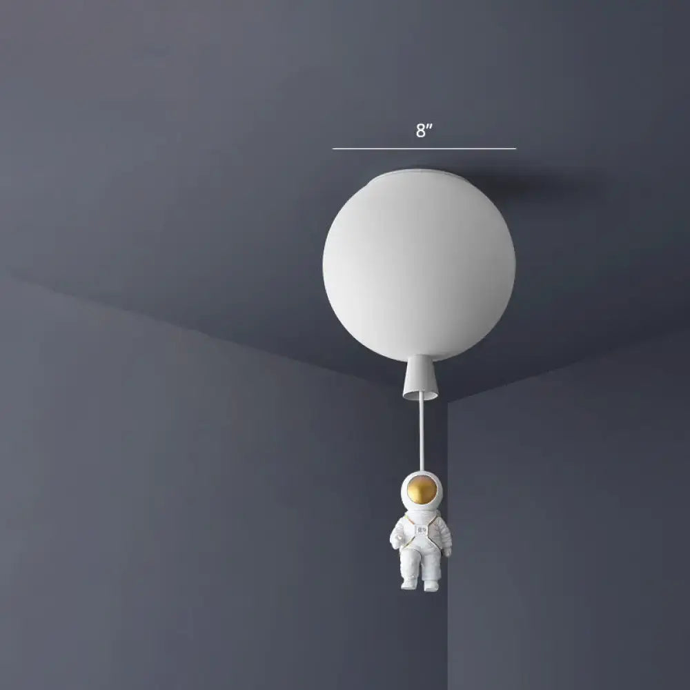 White spherical acrylic pendant light with miniature pink astronaut figure hanging below ceiling lamp for kids room