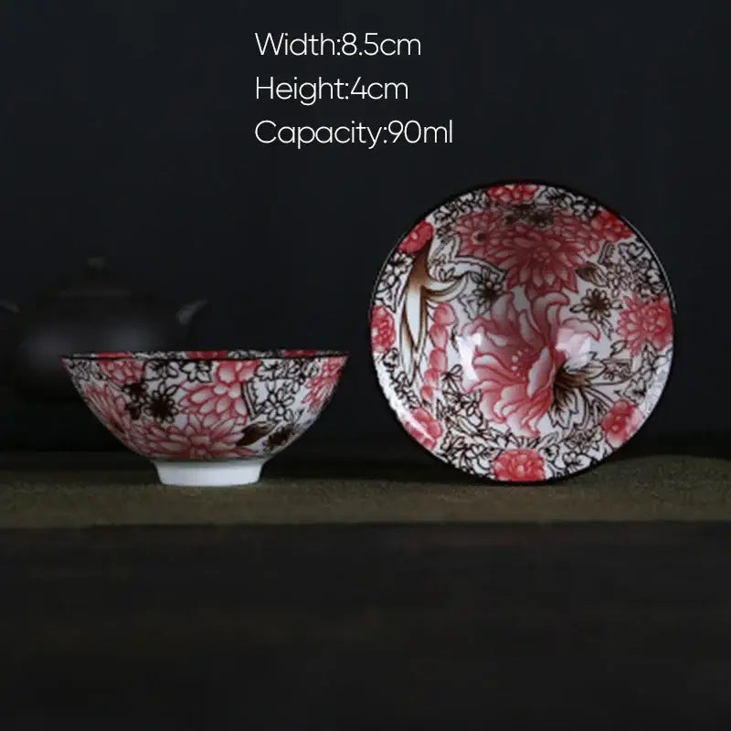 A delicate white porcelain hand-painted tea bowl with vibrant pink and black floral pattern and glossy finish