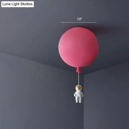 Pink and blue astronaut ceiling lamp featuring a pink balloon-shaped light with a white astronaut figurine pendant