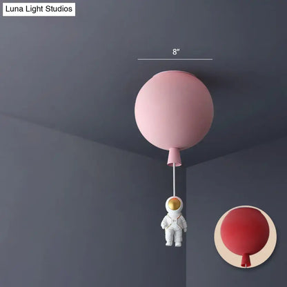 Pink balloon-shaped ceiling lamp with white astronaut figurine hanging below astronaut ceiling lamp for bedrooms