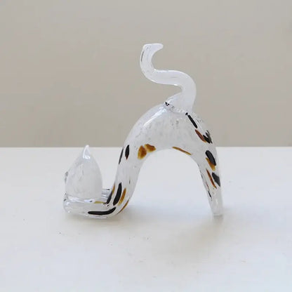 A translucent pink crystal cat figurine with black and brown spots arched in a living room decorbites crystal cat design