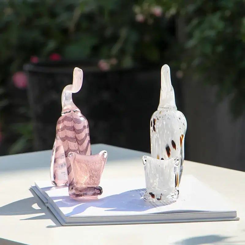 Two translucent glass cat figurines including a pink striped decorbites crystal cat figurine and a clear speckled crystal cat figurine for decor