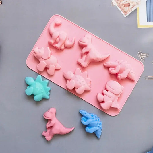 Pink dino silicone cake mold with six cavities and finished pink teal and blue dinosaur shapes for baking use