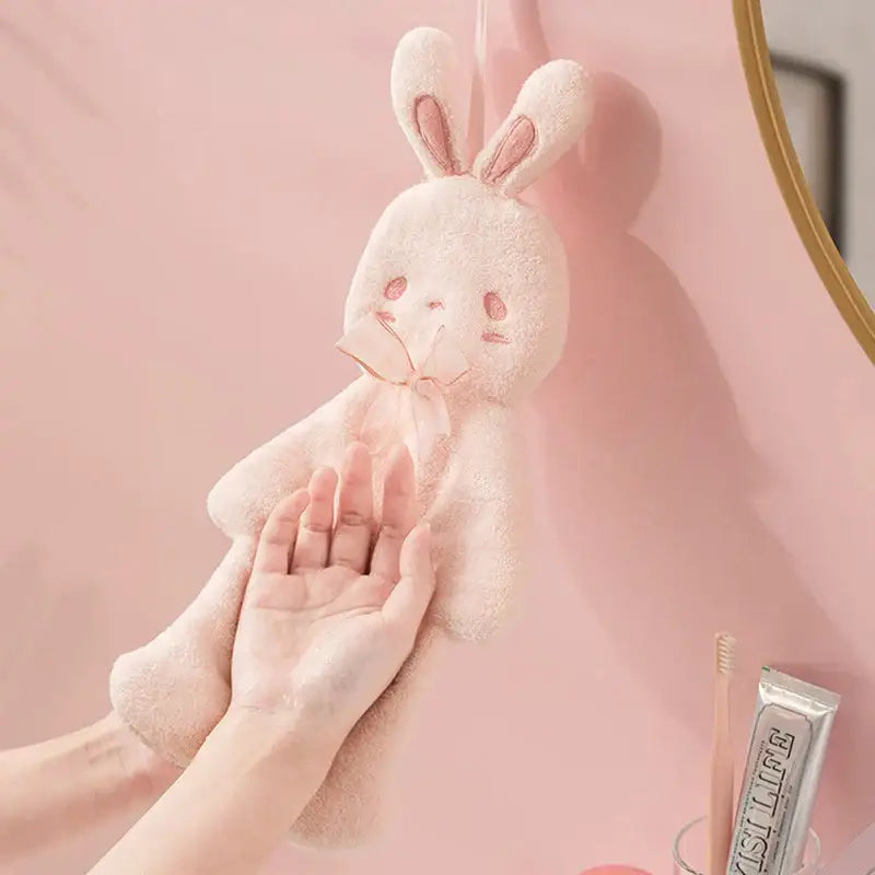 A soft blush-pink plush cartoon rabbit hand towel with embroidered ears and bow tie for bathroom and kitchen use