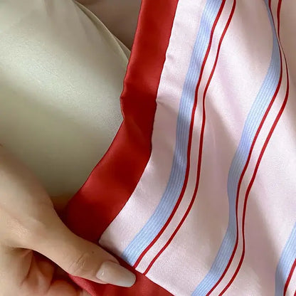 A soft satin-like scarf with bold red and light blue stripes complements a pink decorbites cool lyocell fiber blanket set