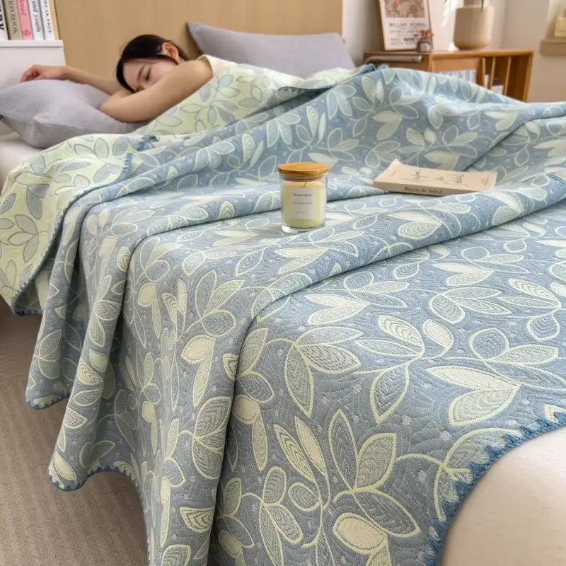 Soft blue quilted decorbites cotton towel blanket with subtle cream and gray leaf pattern and cozy textured surface