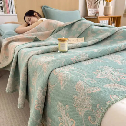 A soft mint green quilted cotton towel blanket with pink and white floral embroidery by decorbites cotton draped on a bed