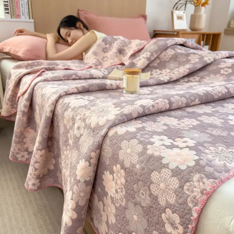 A soft quilted bedroom quilt in muted lavender and blush pink floral patterns with a fringed edge made of decorbites cotton towel