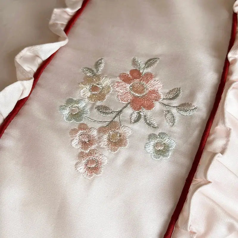 A cream satin pillowcase with intricate floral embroidery and red lace ruffles from decorbites 1000tc cotton bedding set