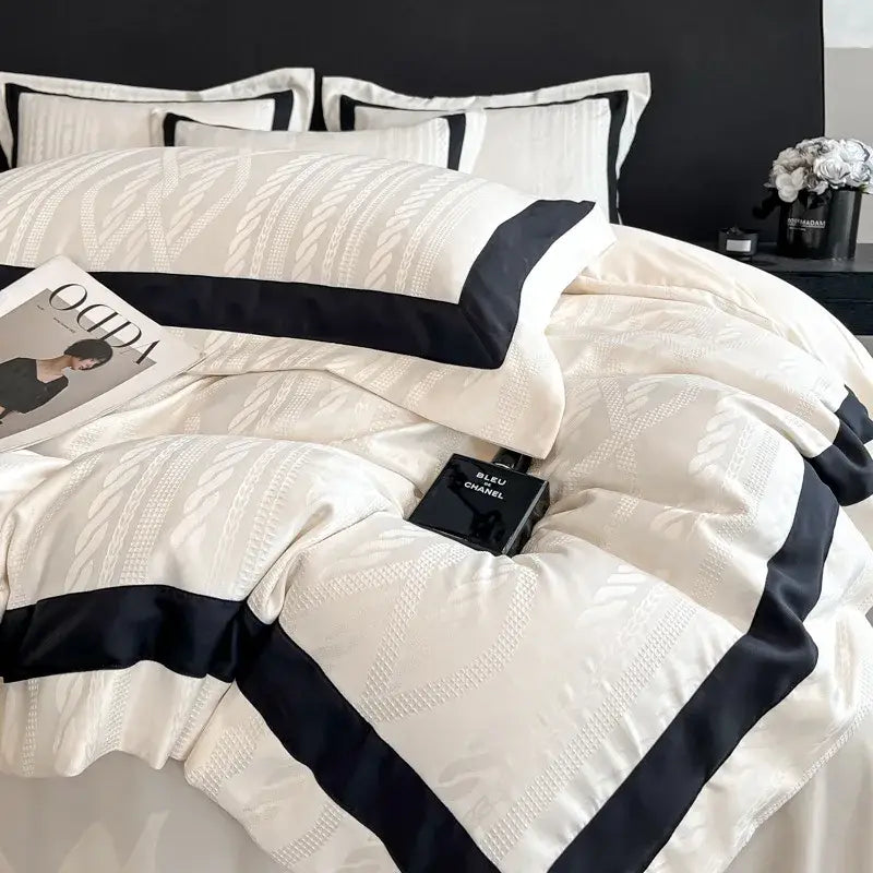 Cream-colored satin duvet cover set with black trim and subtle leaf pattern featuring white piping detail