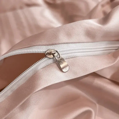 A sleek metallic zipper on soft pink satin jacquard fabric with white piping in a duvet cover set