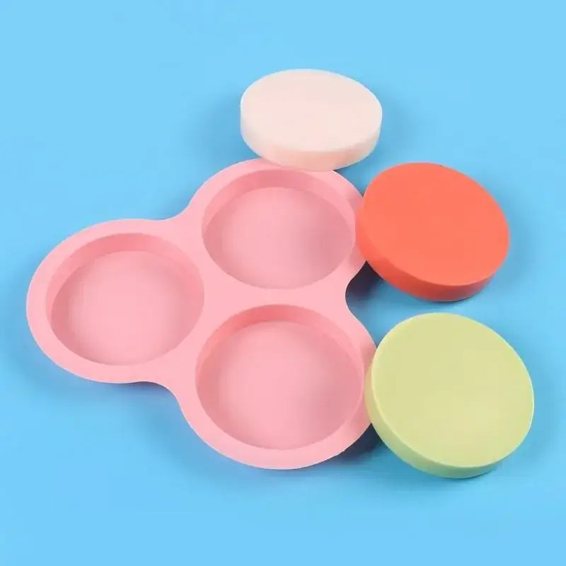 Pink silicone egg mold pancake shaper kitchen muffin pan with four cavities and three matching round cake molds beside it