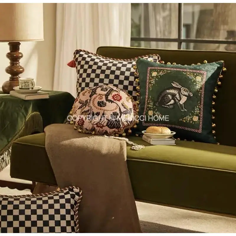 Emerald green velvet cushion cover with embroidered rabbit design and gold-toned pom-pom trim for living room decor