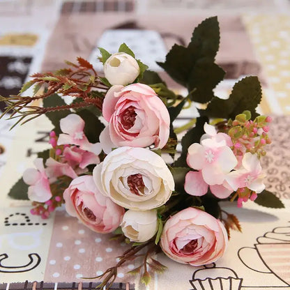A delicate silk tea rose ranunculus bouquet in pink and white with green leaves for wedding decor