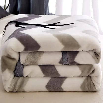 A plush black and white chevron winter raschel blanket with a gray and white geometric pattern and a black deer antler design