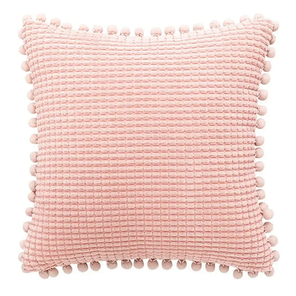 A soft pink waffle-textured pillow with pom-pom trim shown alongside a plush black and white decorbites houndstooth cushion cover