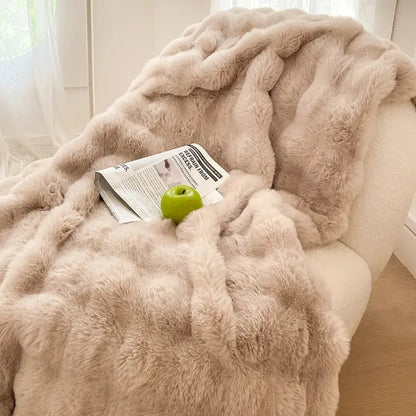 A plush cream and gradient pink double layer faux fur throw blanket with soft fluffy texture draped over an armchair