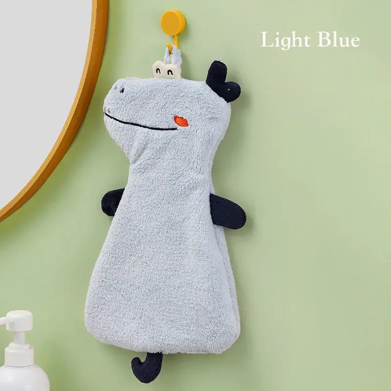 Light blue plush dinosaur hand towel with black accents and orange nose made of double-layer coral velvet hanging on yellow hook