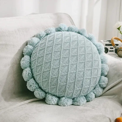 A soft light blue knitted round pillow with fluffy pom-poms complementing plush white and soft pink decorbites 3d flowers pillows for home decor