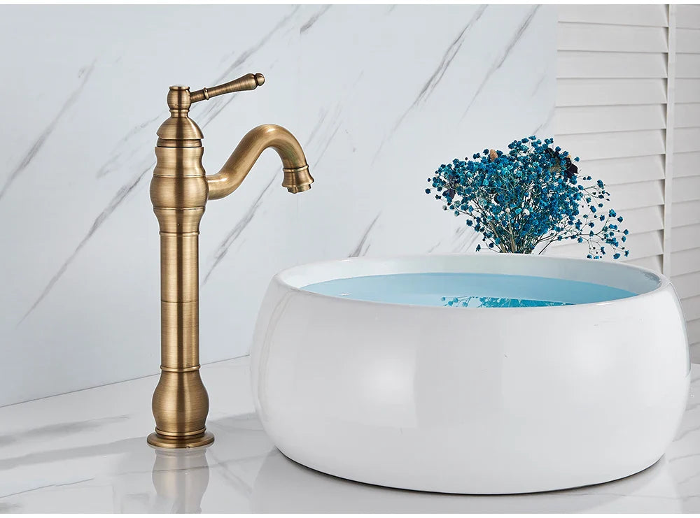 Antique brass single hole deck mounted bathroom faucet with curved spout made of durable housing material beside white vessel sink