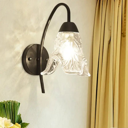 Post-modern black metal wall sconce with a clear crystal shade and intricate textured glass for bedroom use
