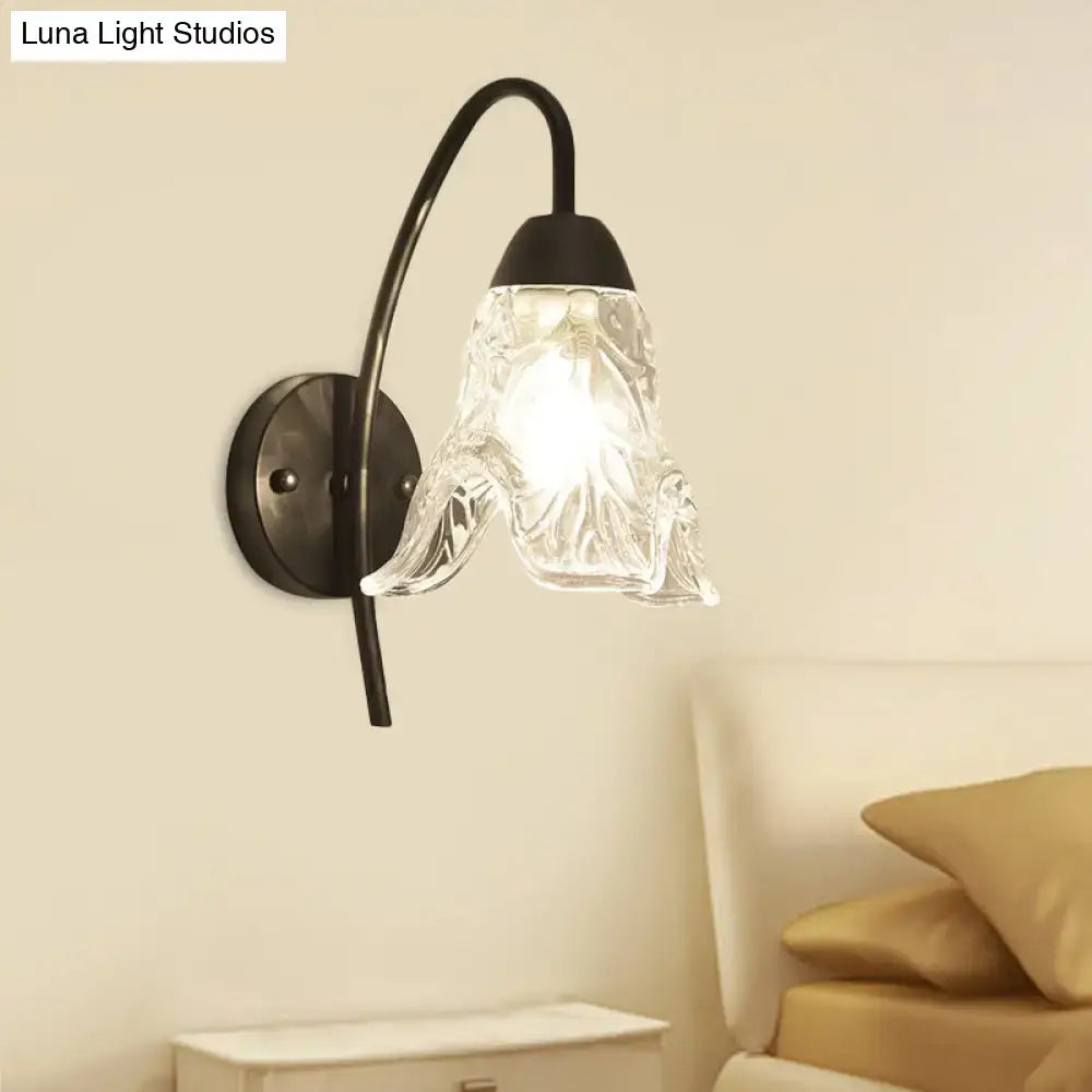 Post-modern black metal wall sconce with clear crystal shade shaped like an open flower for bedroom use