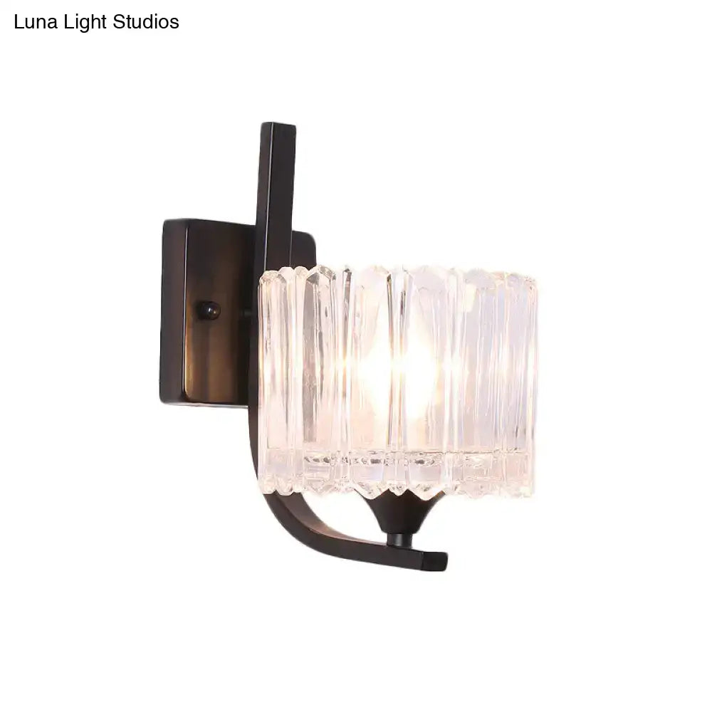 Post-modern black metal wall sconce with a clear crystal shade featuring a vertically ribbed glass design for bedroom use