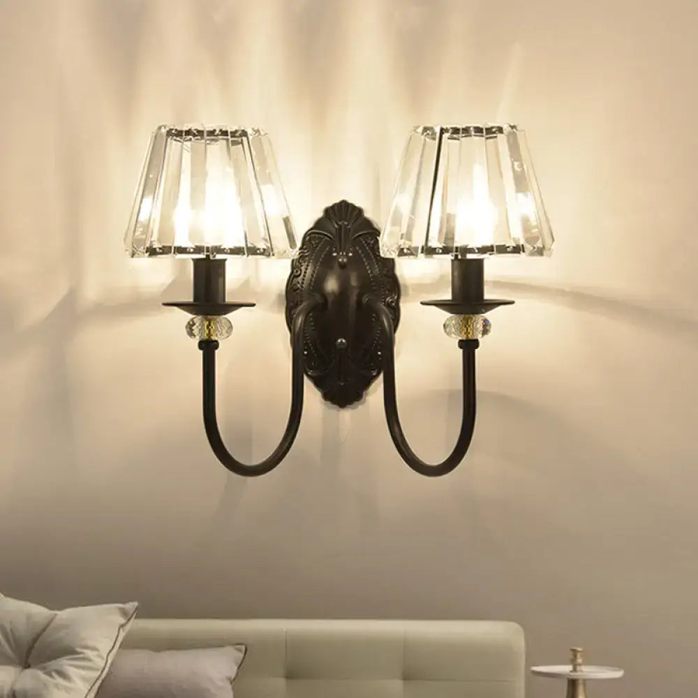 Antique bronze two-light wall sconce with black metal frame and clear crystal prismatic shades for bedroom use