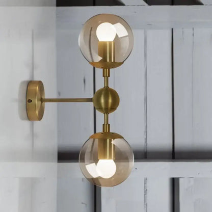 Post modern brass wall light with two spherical amber glass shades compatible with e26 e27 bulbs for bedroom use