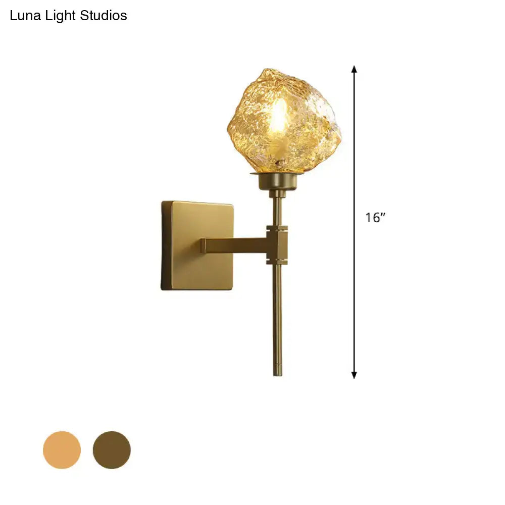 Post modern brass and amber glass wall light sconce with a textured amber-gold glass globe for living room use