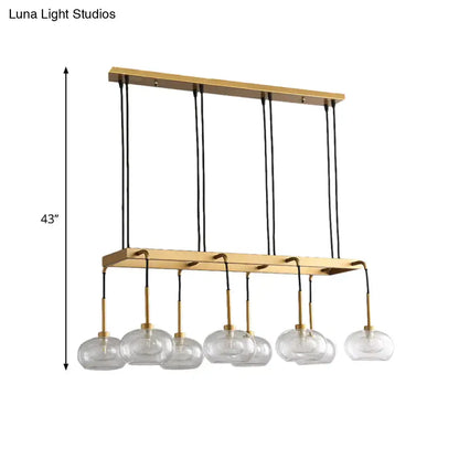 Gold-toned post-modern island chandelier with six clear glass globe shades suspended by black cords by DecorBites