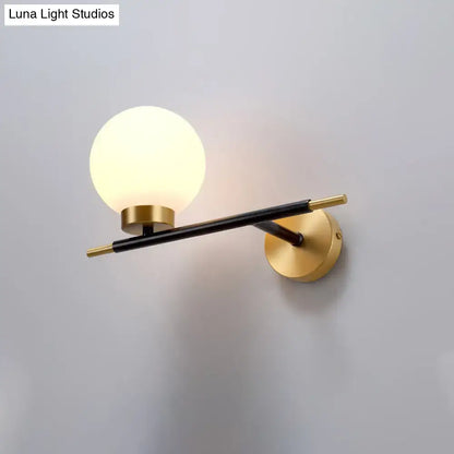 Modern post-modern sphere wall sconce with frosted glass globe black and brass accents for bedroom lighting