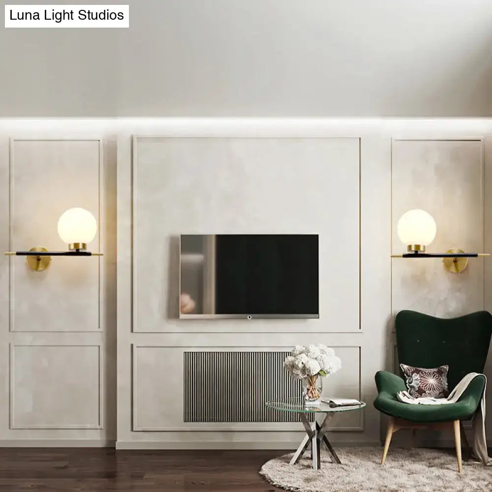 Gold finished sphere wall sconce with minimalist black bar base for bedroom lighting in post modern style