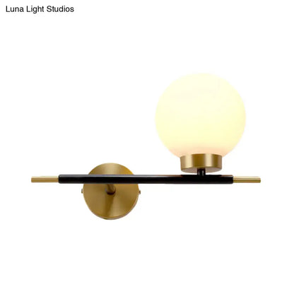 Post-modern sphere wall sconce with matte black bar, gold-toned accents, and frosted glass globe for bedroom lighting