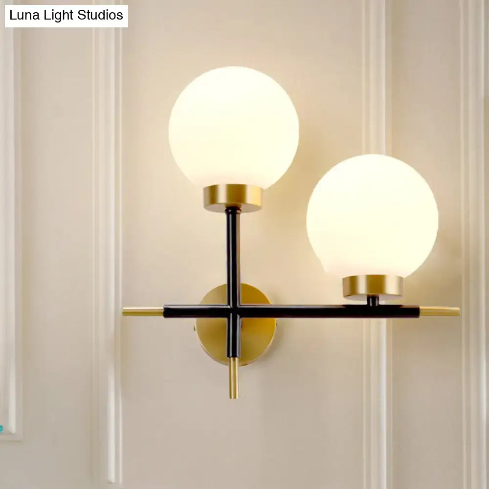 Modern post-modern sphere wall sconce with frosted glass globes and black and gold metal frame for bedroom lighting