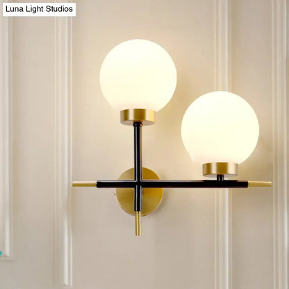 Modern post-modern sphere wall sconce with frosted glass globes and black and gold metal frame for bedroom lighting