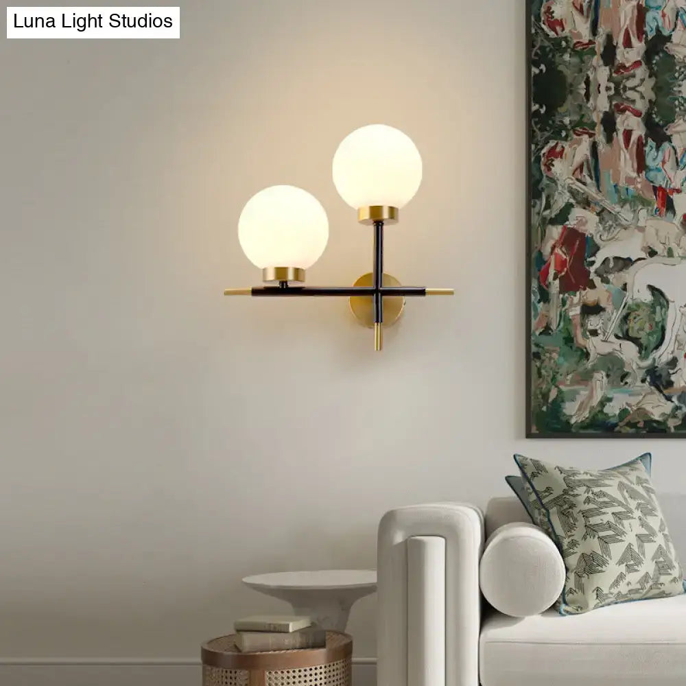 Post-modern white and brass sphere wall sconce with frosted glass globes and black metal frame for bedroom lighting