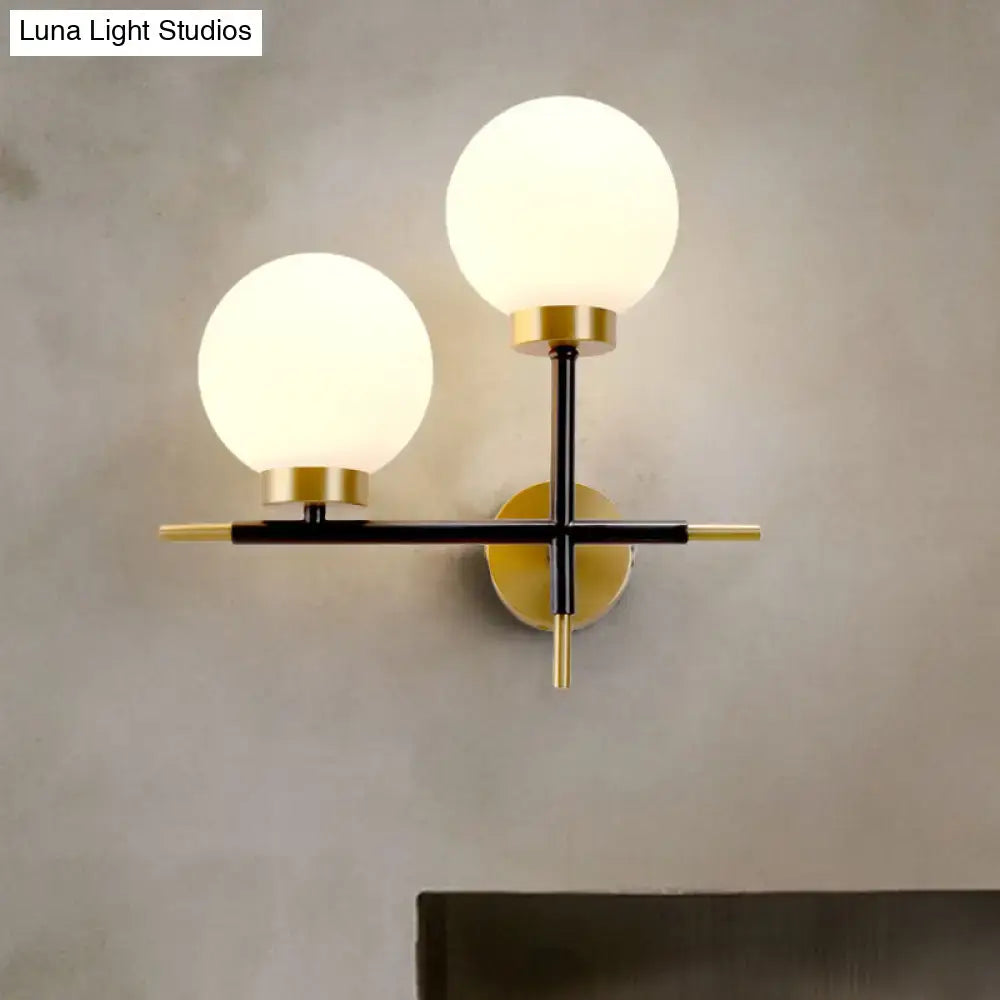 Modern two-light sphere wall sconce with frosted glass globes and black and gold metal frame for bedroom lighting
