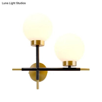 Modern sphere wall sconce with frosted glass globes and black and gold metal frame for bedroom lighting