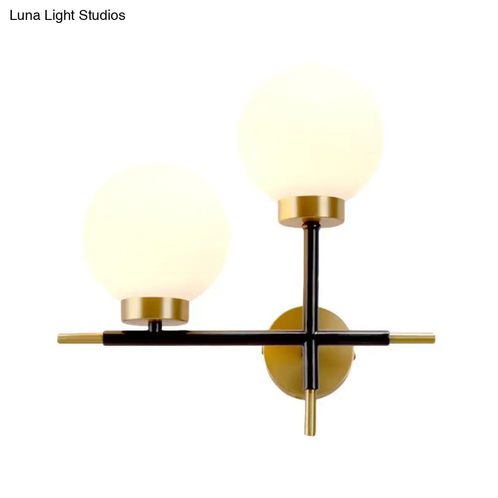 Modern two-light sphere wall sconce with matte black and brass accents and frosted glass globe shades for bedroom use