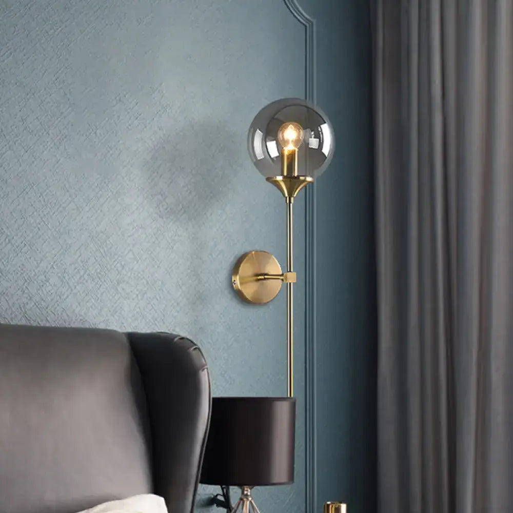 Gold-toned postmodern wall sconce with smoke grey spherical glass and exposed filament e26 e27 bulb for bedroom use
