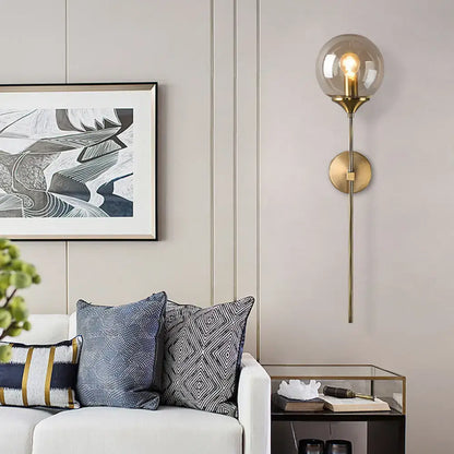 A modern wall sconce with smoke grey spherical glass shade and brass base designed for e26 e27 bulb use