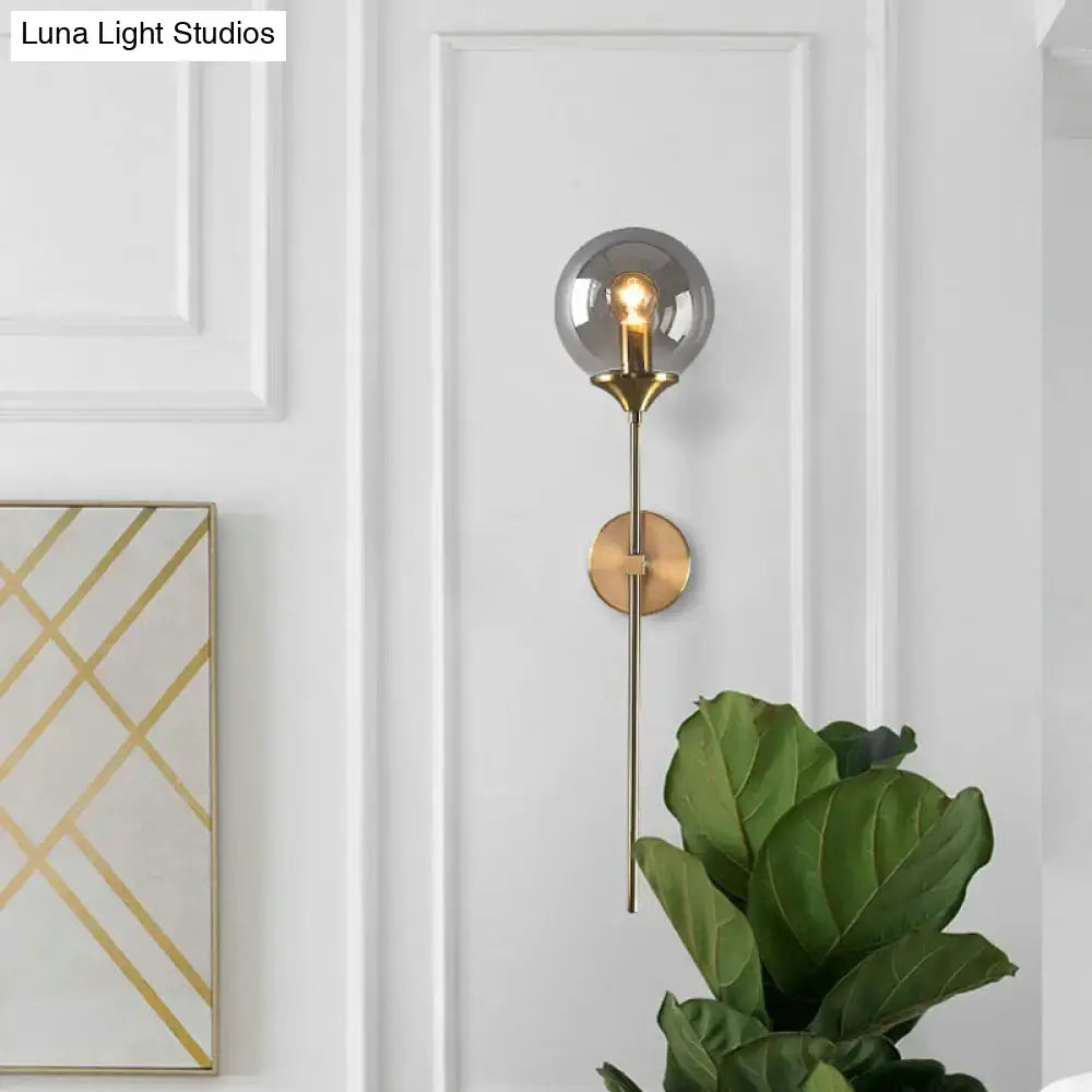 Postmodern wall sconce with brushed brass finish and smoke grey spherical glass shade for e27 bulb use